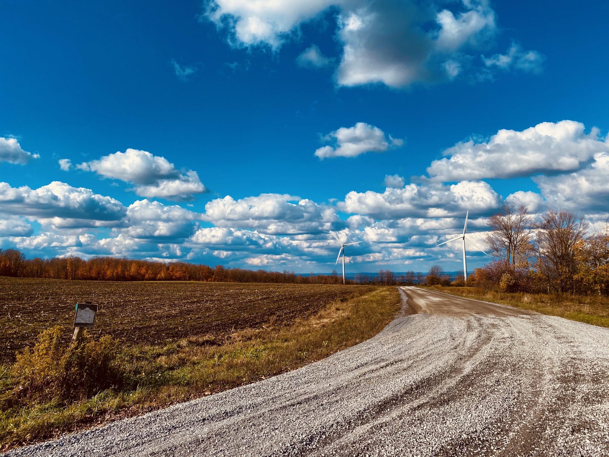 照片的土路与风车和蓝天/云的背景